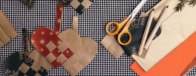 Aerial view of craft supplies and three paper woven hearts